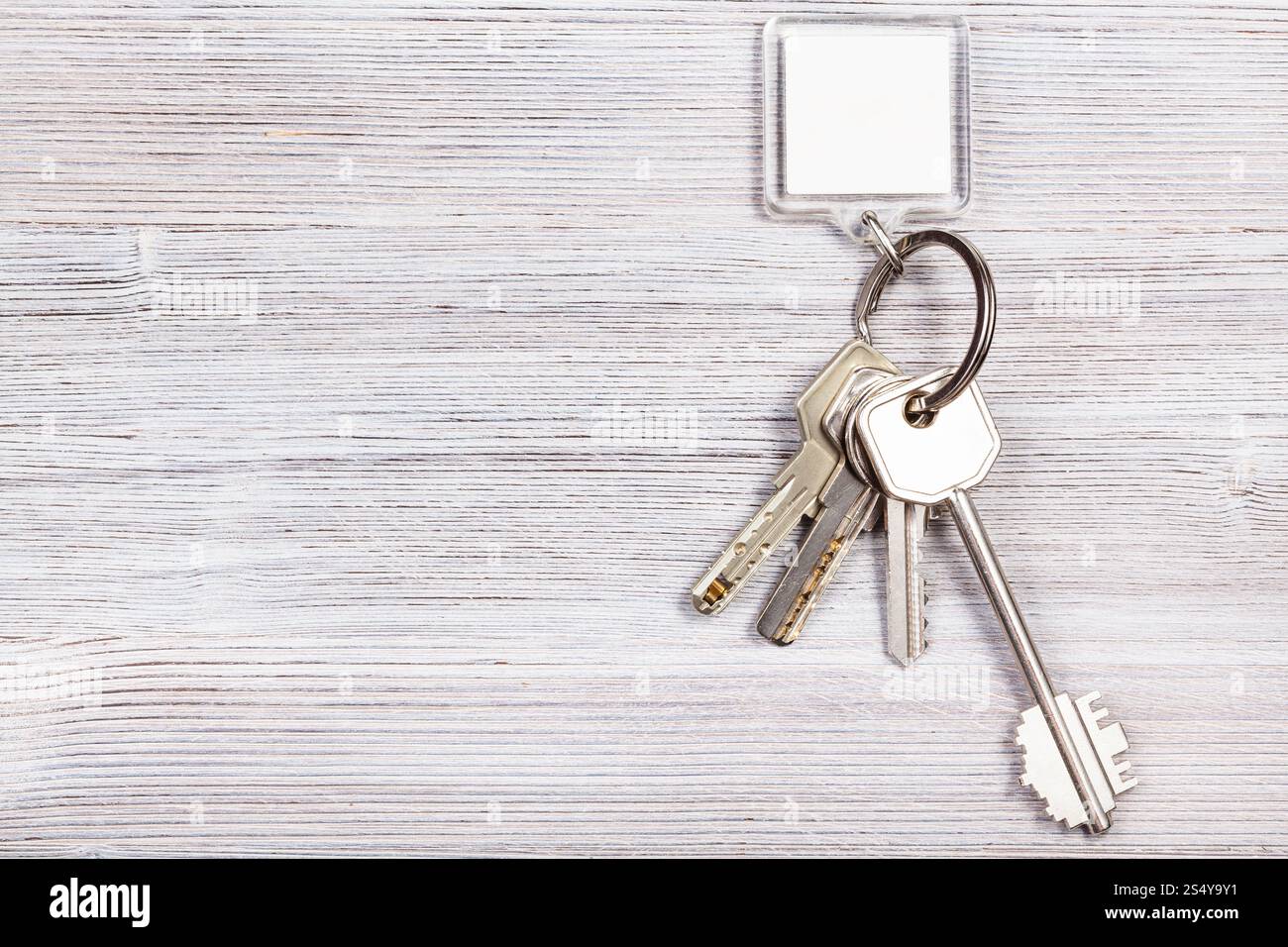 Mazzo di chiavi della porta con il bianco chiave vergine catena sul pannello di legno Foto Stock