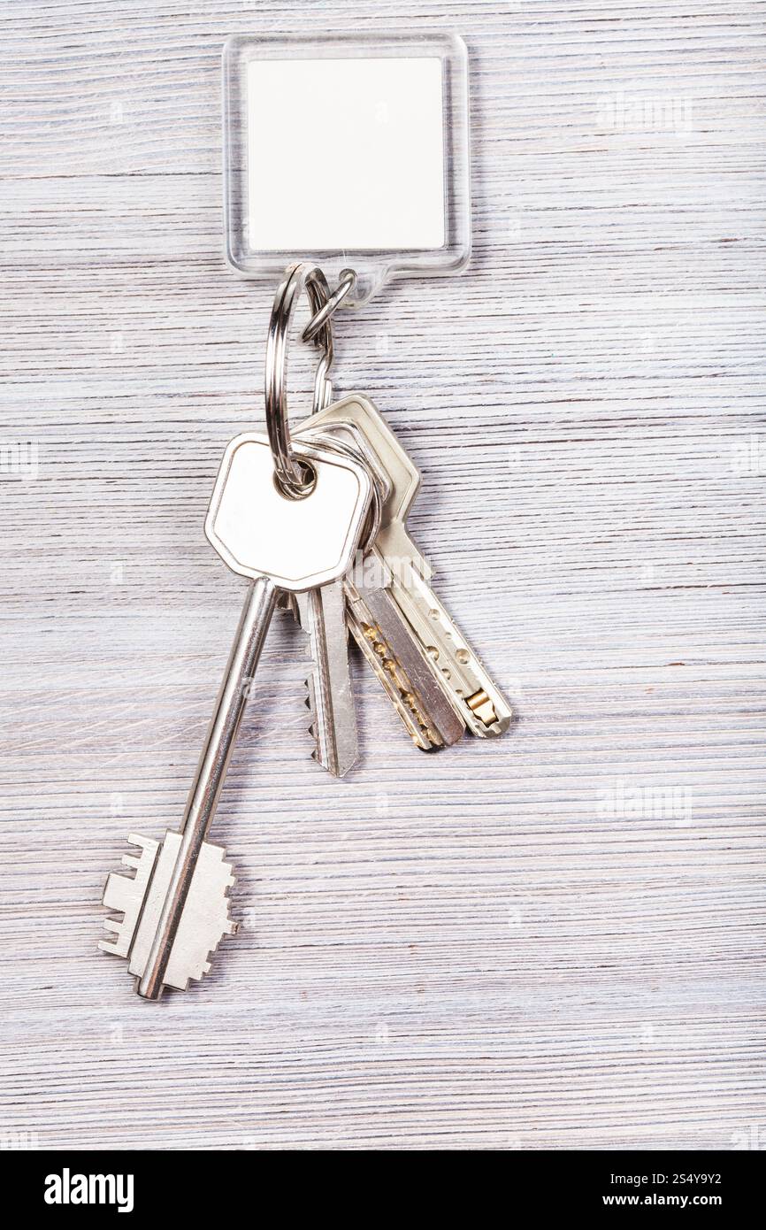 Mazzo di chiavi della porta con il bianco chiave vergine catena su sfondo di legno Foto Stock