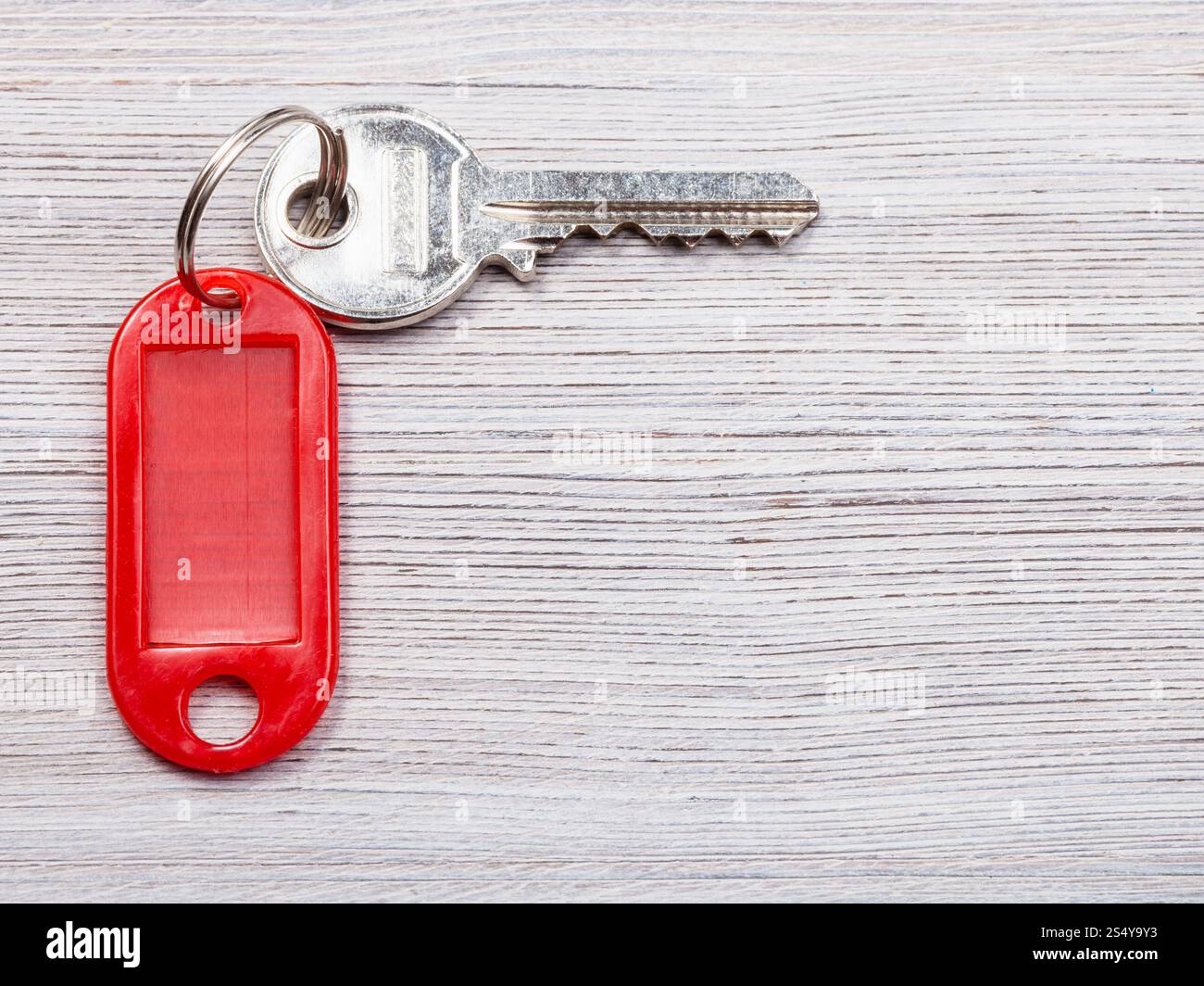 La chiave della porta di rosso con una chiave vergine catena su sfondo di legno Foto Stock