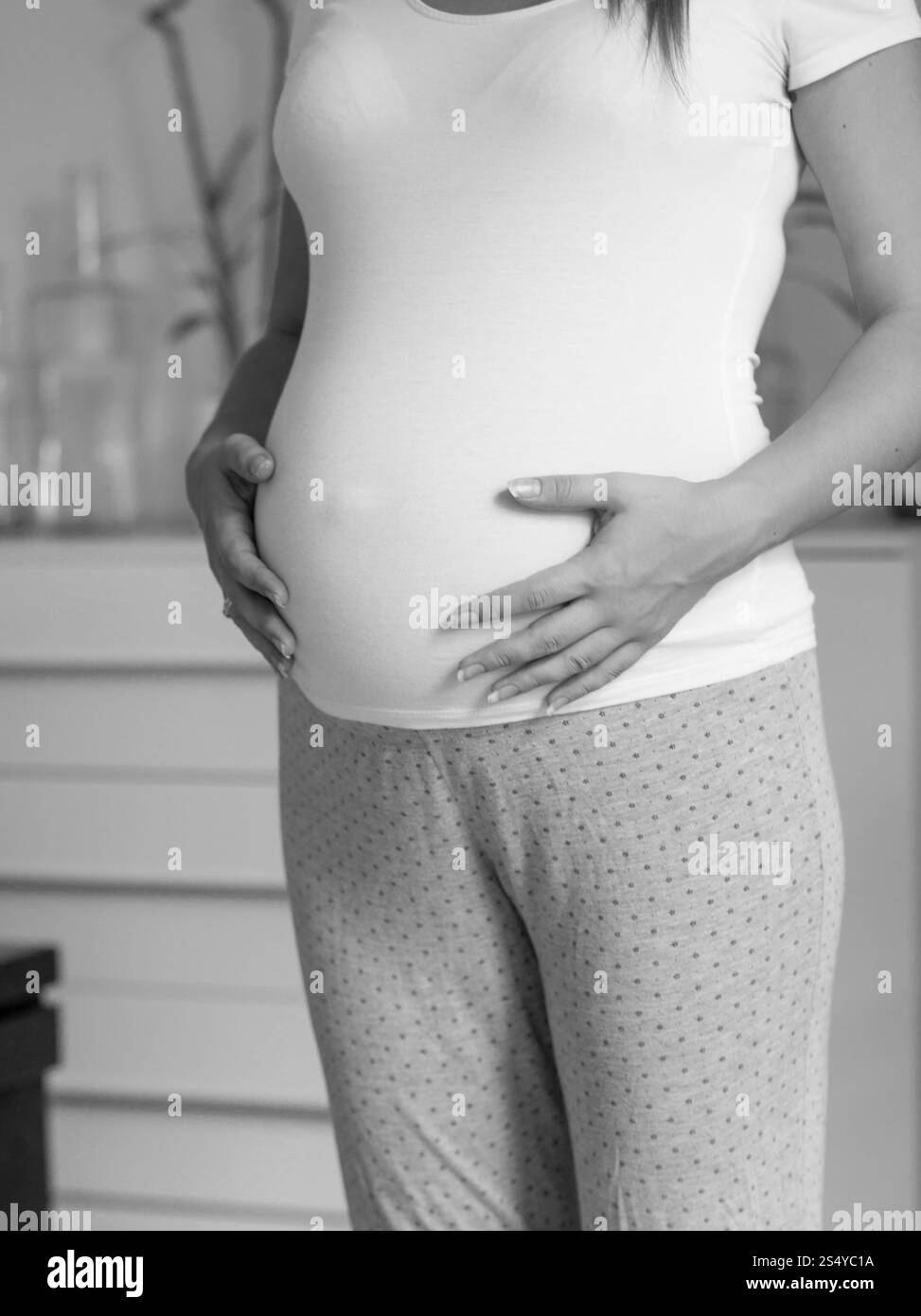 Bianco e nero bella donna incinta in t-shirt bianca che tocca la pancia grande Foto Stock