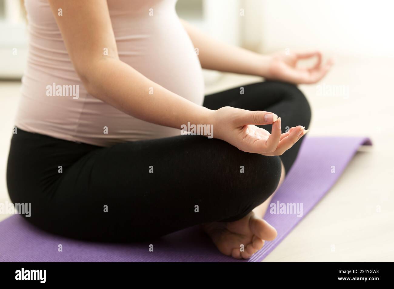 Foto ravvicinata di una donna incinta che pratica yoga sul pavimento a casa Foto Stock