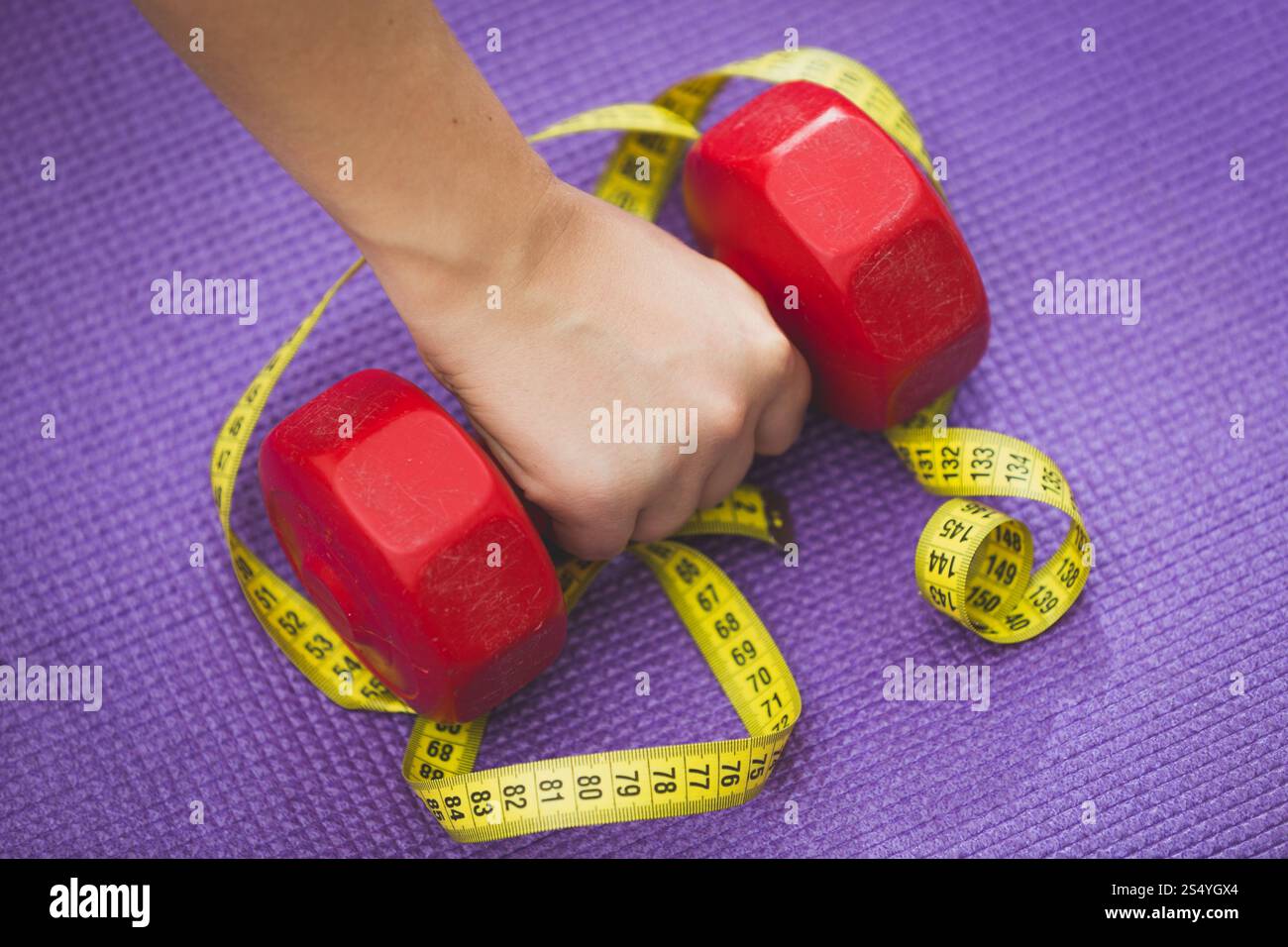 Primo piano di manubrio femmina per il sollevamento delle mani adagiato su nastro di misurazione giallo Foto Stock