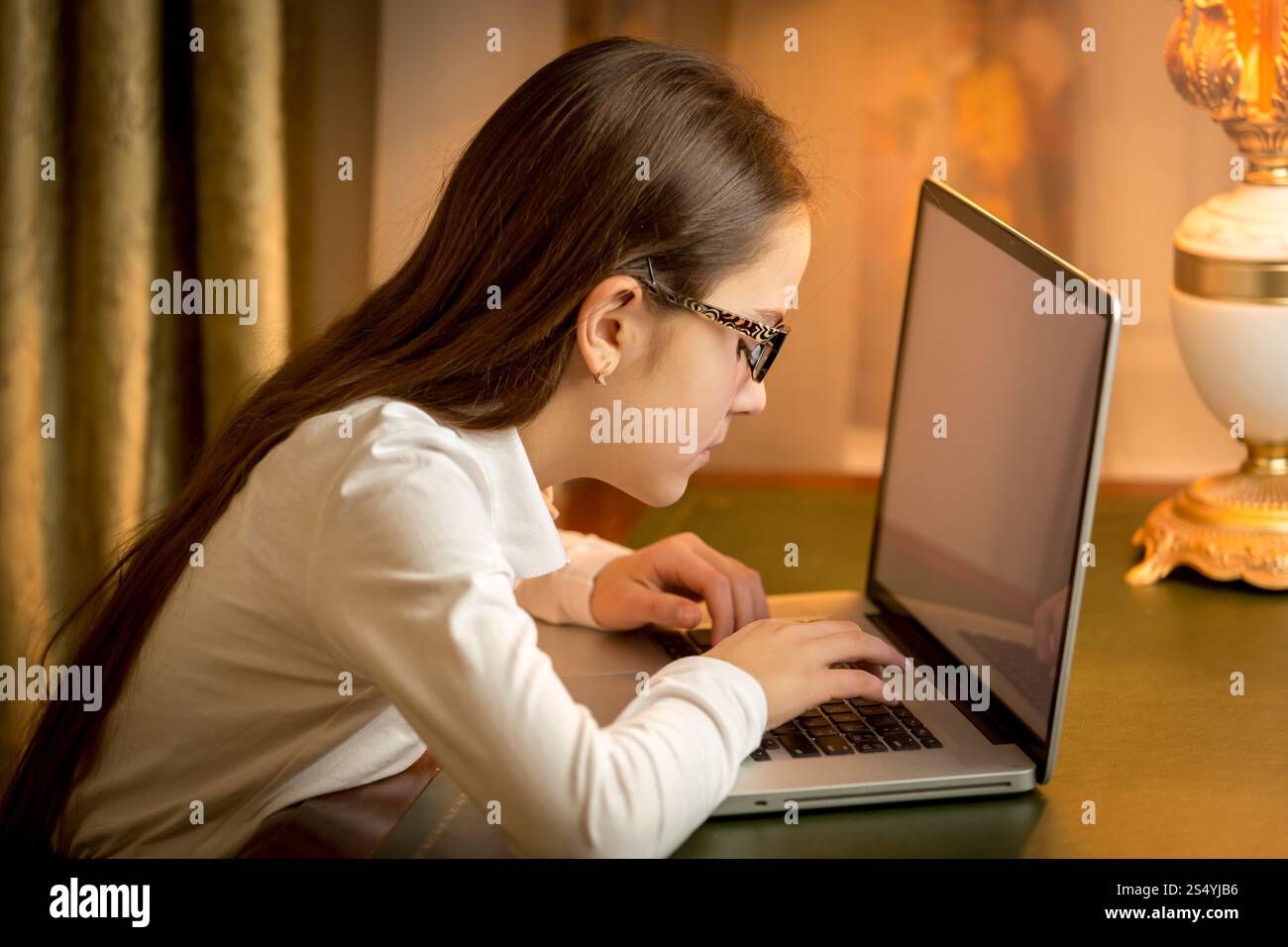 Ritratto di una ragazza adolescente con una cattiva vista che scrive un messaggio sul laptop Foto Stock Ritratto di una ragazza adolescente con una cattiva vista che scrive un messaggio sul laptop Foto Stock