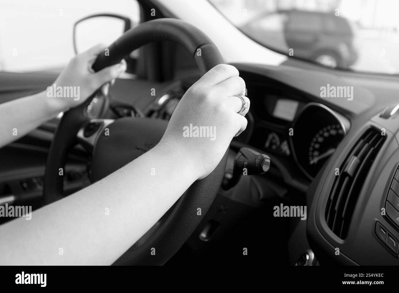 Primo piano immagine in bianco e nero di una donna che tiene il volante dell'auto Foto Stock
