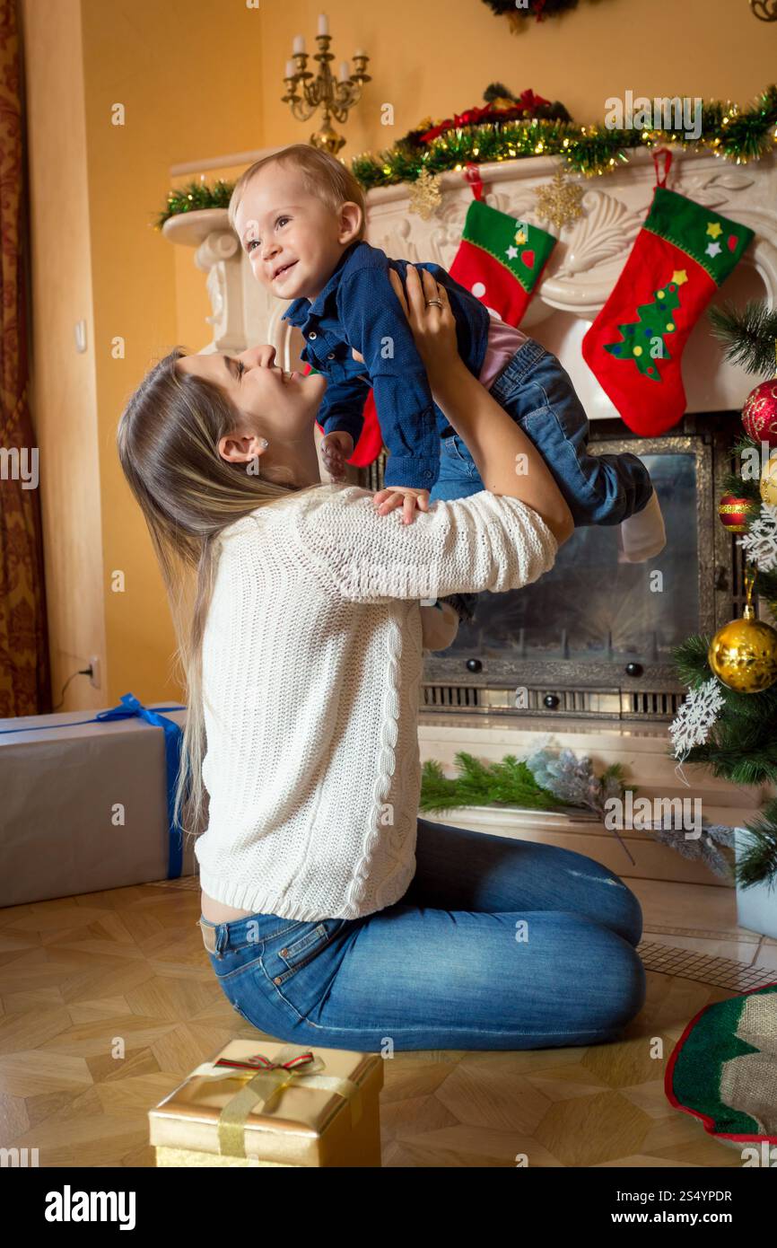Allegra madre che gioca con il suo bambino di 1 anno all'albero di Natale Foto Stock