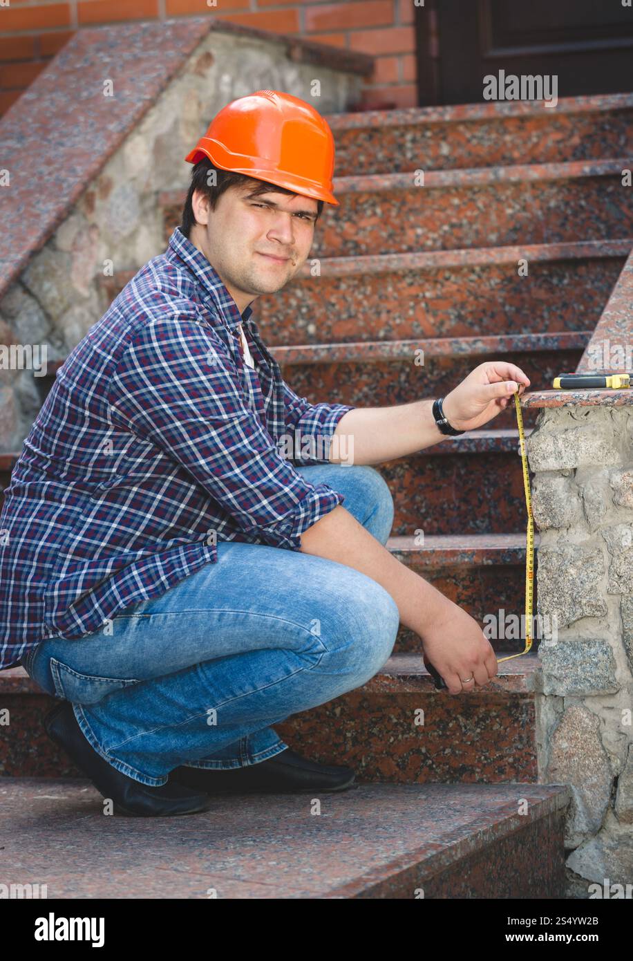 Lavoratore con casco rosso che ripara la vecchia scala in pietra Foto Stock