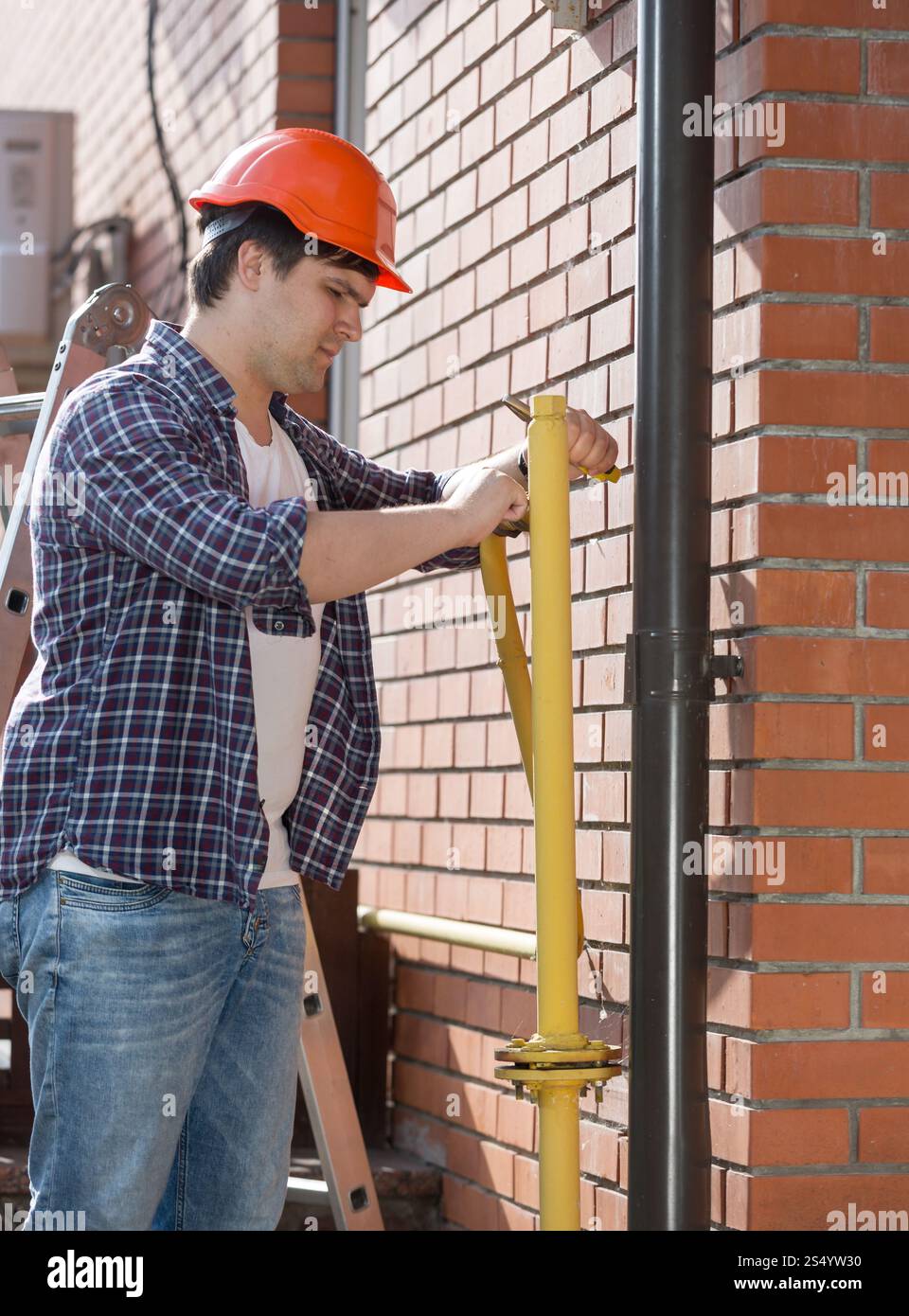 Idraulico in elmetto che ripara tubi in casa Foto Stock