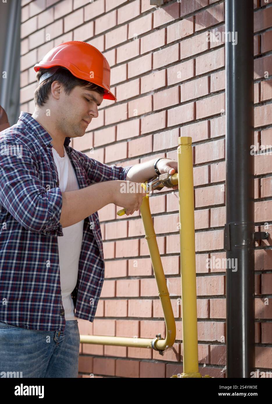 Giovane idraulico in elmetto per la riparazione di tubi Foto Stock