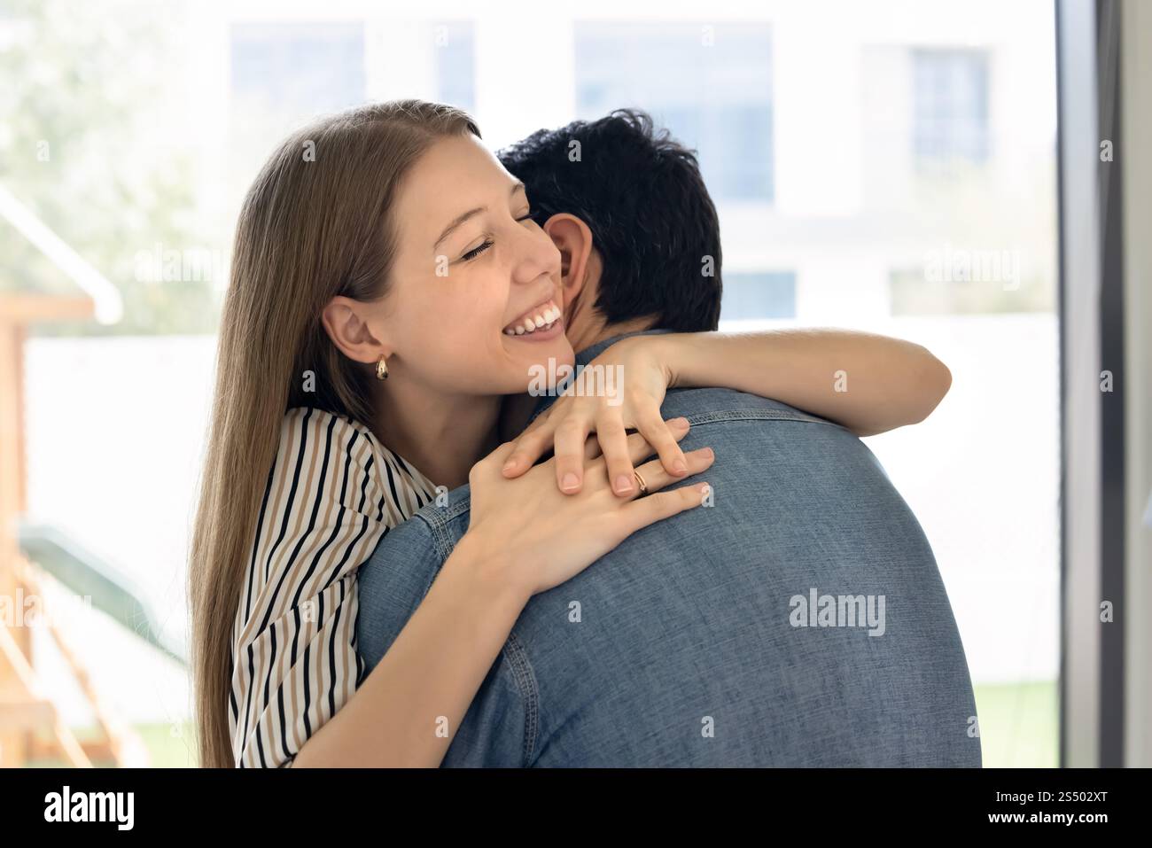 Felice eccitata giovane moglie che abbraccia marito a occhi chiusi Foto Stock