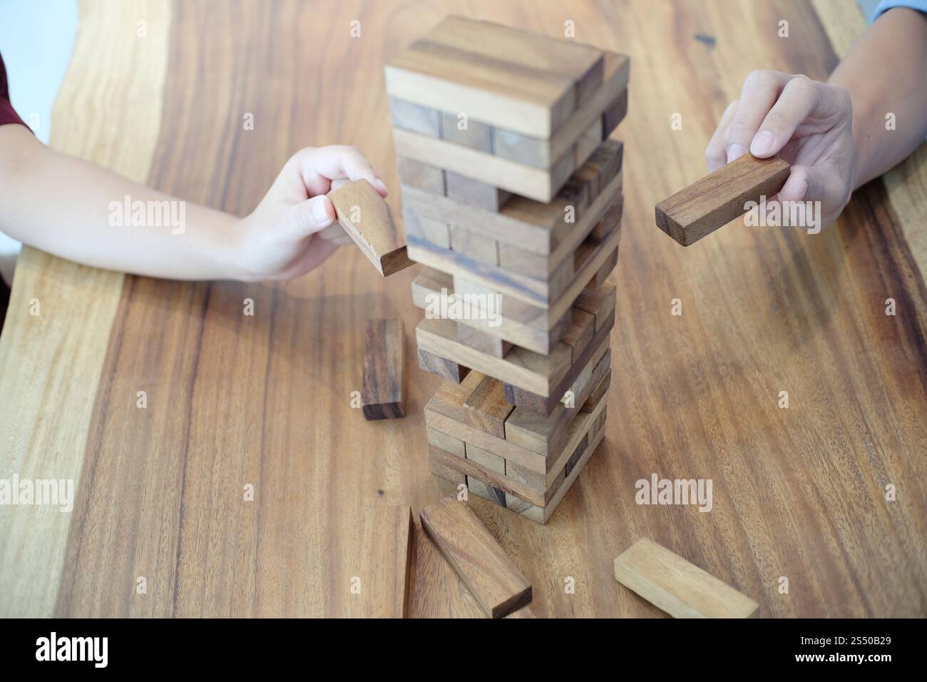Gruppo di amici che gioca blocchi gioco di legno sul tavolo puzzle piegato Foto Stock