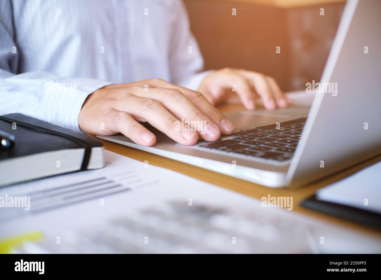 Uomo al lavoro utilizzando un computer portatile su un tavolo di legno. Mani digitando su una tastiera. Foto Stock