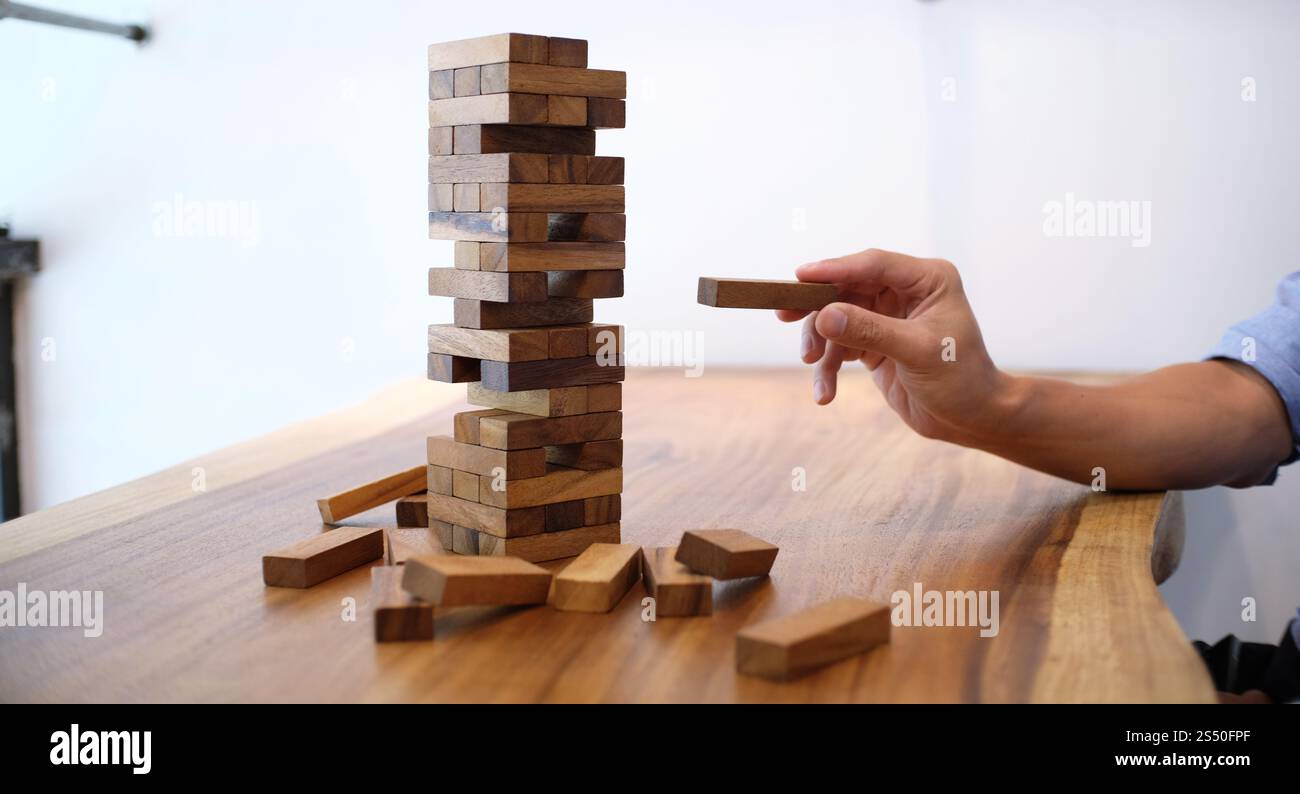 Gruppo di amici che gioca blocchi gioco di legno sul tavolo puzzle piegato Foto Stock