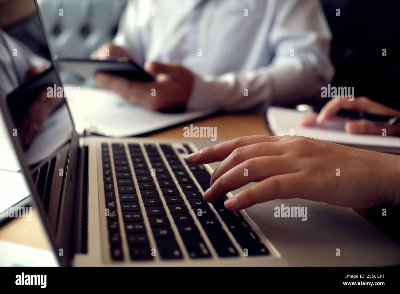 Uomo al lavoro utilizzando un computer portatile su un tavolo di legno. Mani digitando su una tastiera. Foto Stock