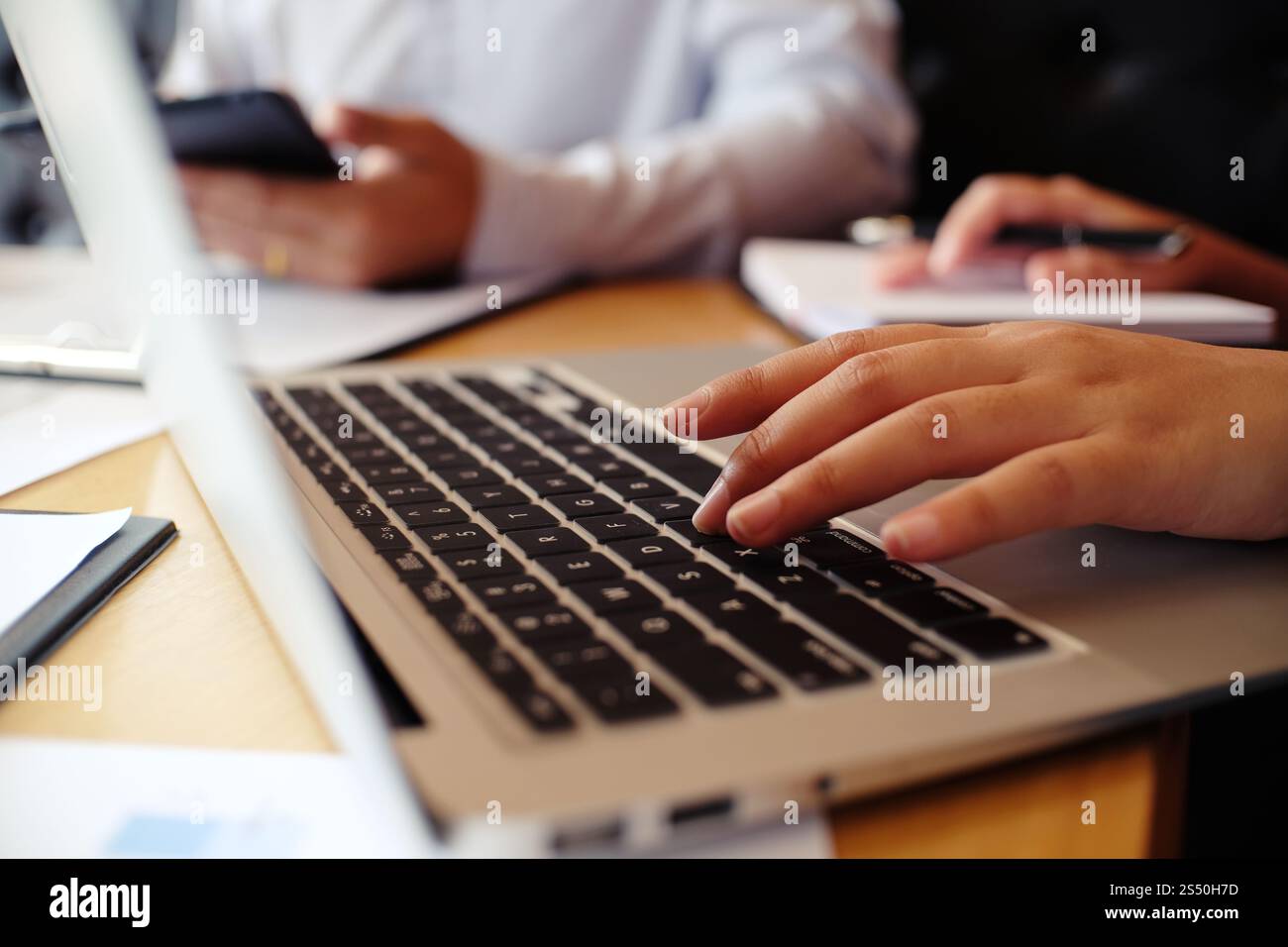 Uomo al lavoro utilizzando un computer portatile su un tavolo di legno. Mani digitando su una tastiera. Foto Stock