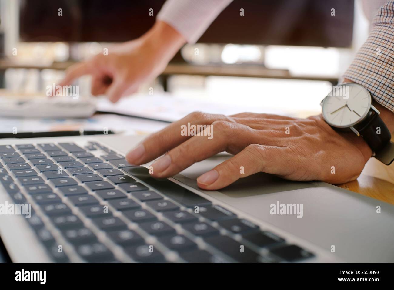 Uomo al lavoro utilizzando un computer portatile su un tavolo di legno. Mani digitando su una tastiera. Foto Stock