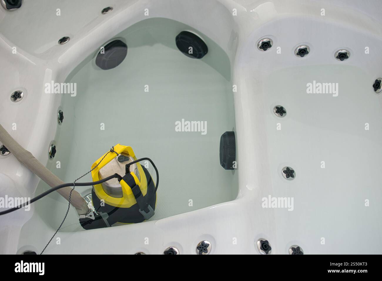 Pompa sommergibile in acciaio inox con manico giallo brillante e supporti per tubi in acqua idromassaggio. Concentrati sulla pompa. Filo collegato e cavo di alimentazione visibile Foto Stock