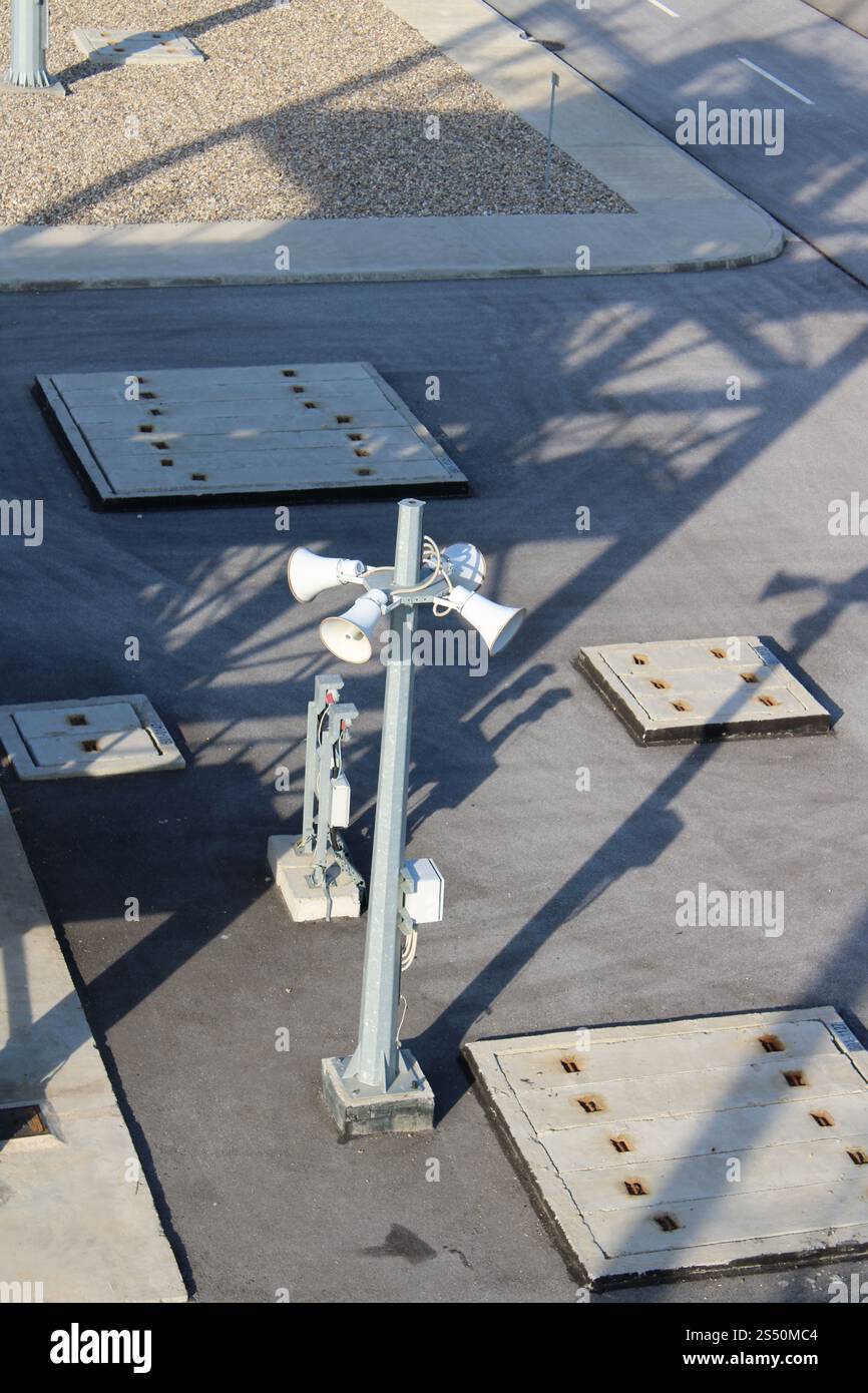 Un palo con diversi altoparlanti e componenti elettrici in un'area industriale Foto Stock