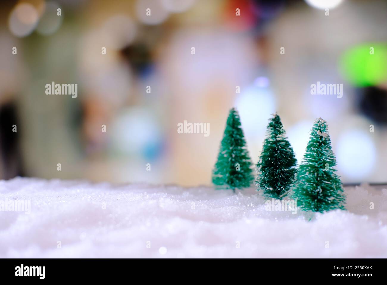 Natale decorazione della casa con un piccolo dono fatti a mano box in una coperta di neve in miniatura della foresta sempreverde e bokeh luce per lo spazio di copia Foto Stock