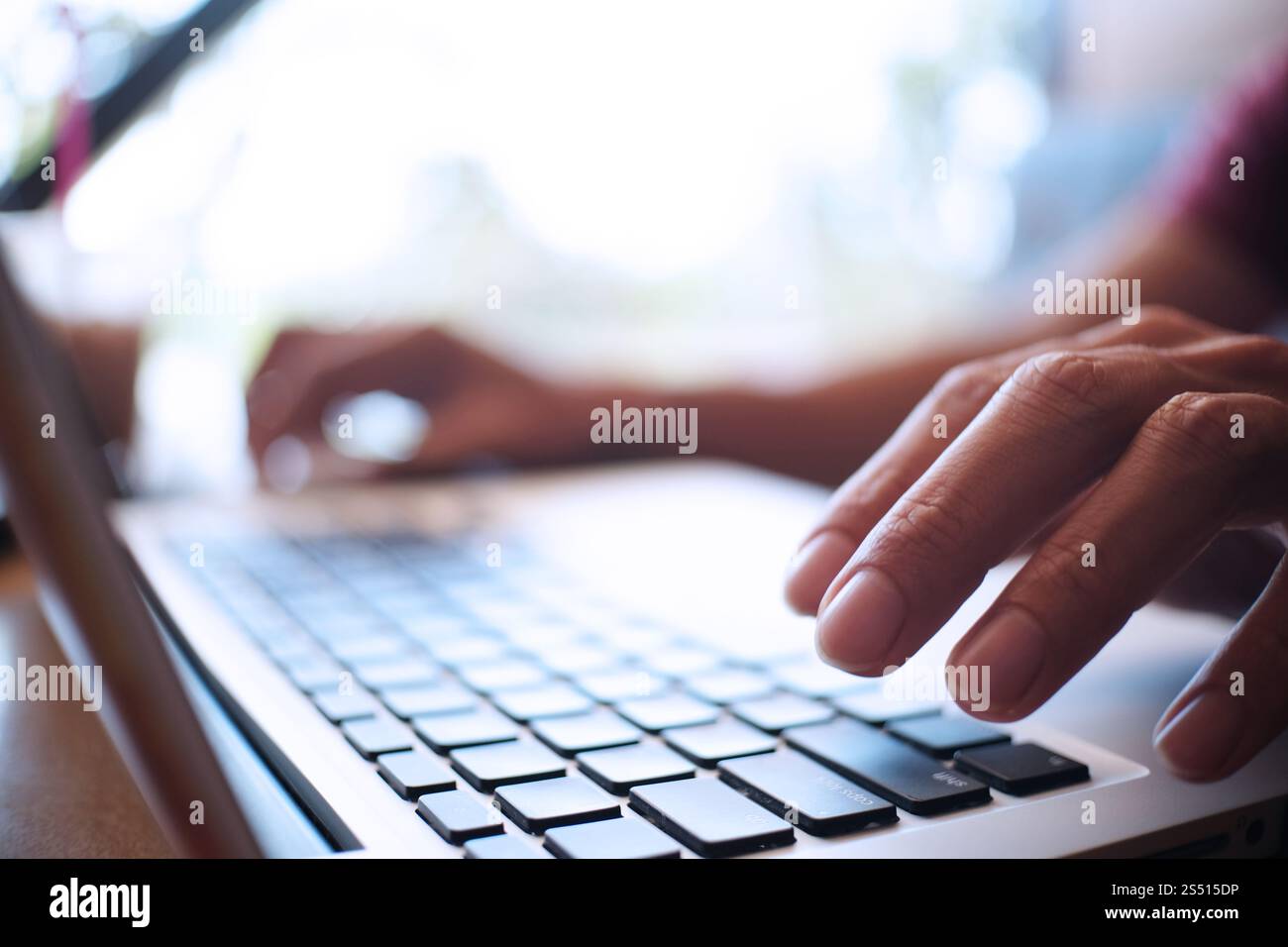 Uomo al lavoro utilizzando un computer portatile su un tavolo di legno. Mani digitando su una tastiera. Foto Stock