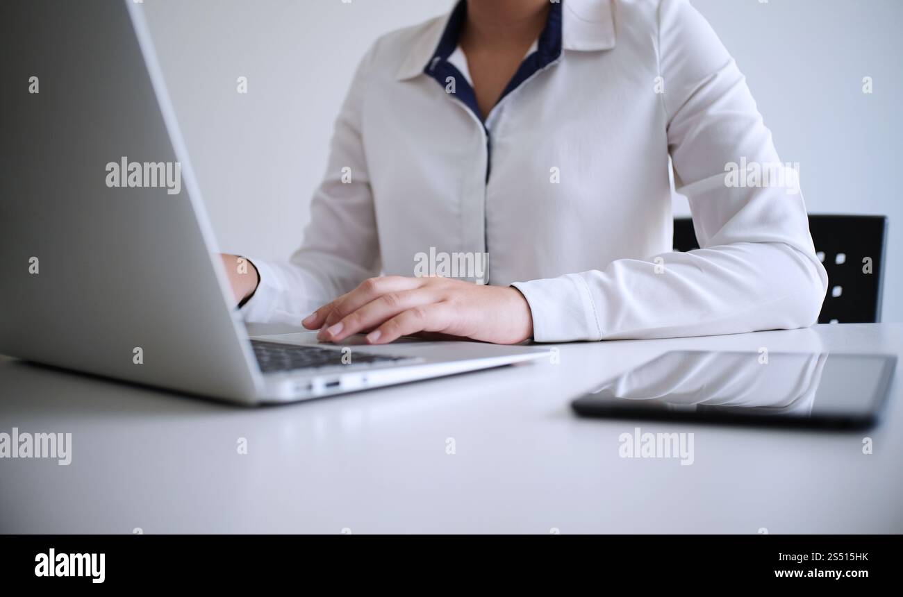 Uomo al lavoro utilizzando un computer portatile su un tavolo di legno. Mani digitando su una tastiera. Foto Stock