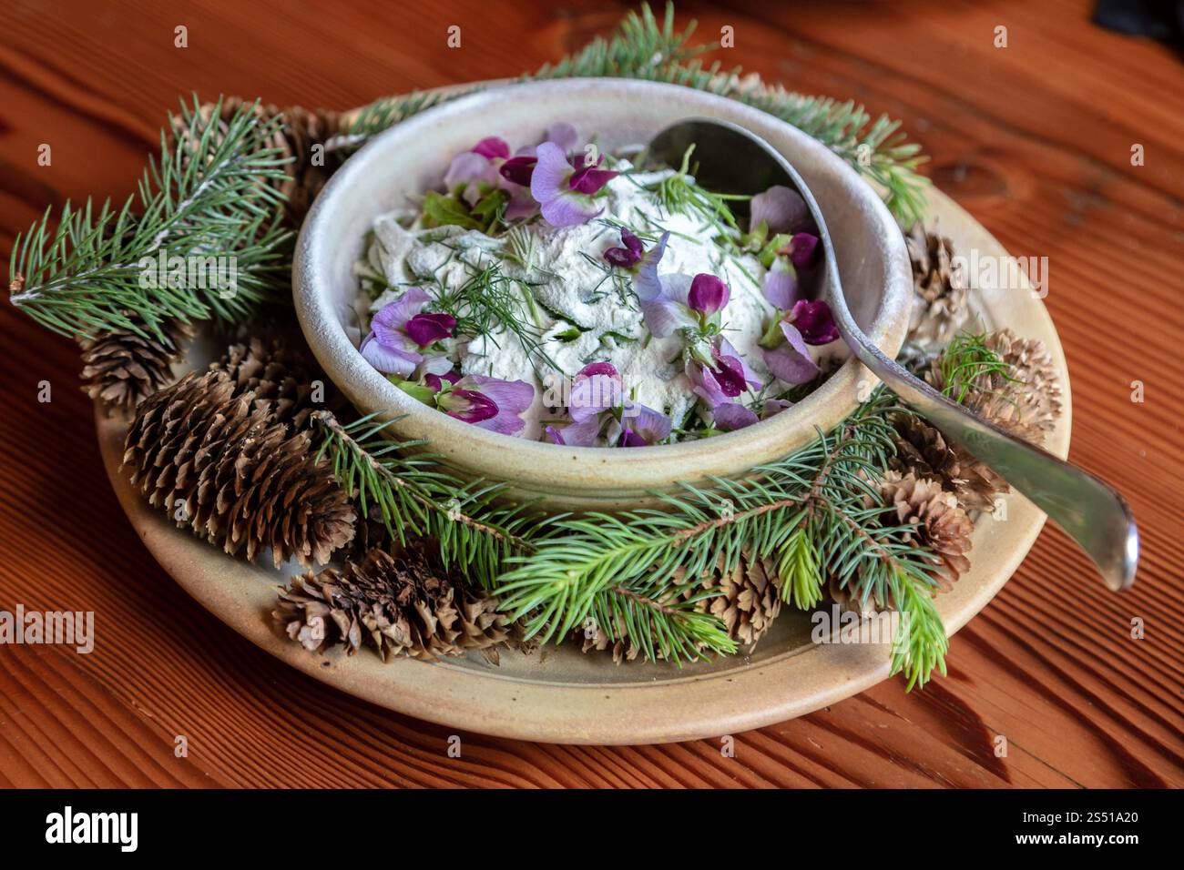 Bella tavola con yogurt, fiori commestibili ed elementi forestali su un tavolo rustico Foto Stock