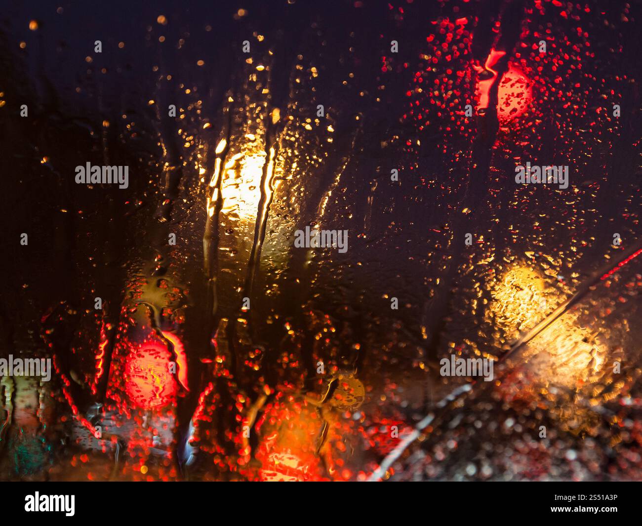 Guidare nelle nevicate notturne a Mosca - triciclo d'acqua dallo scioglimento della neve sul parabrezza dell'auto la sera d'inverno (concentrarsi sul vetro del finestrino dell'auto anche se bagnato Foto Stock