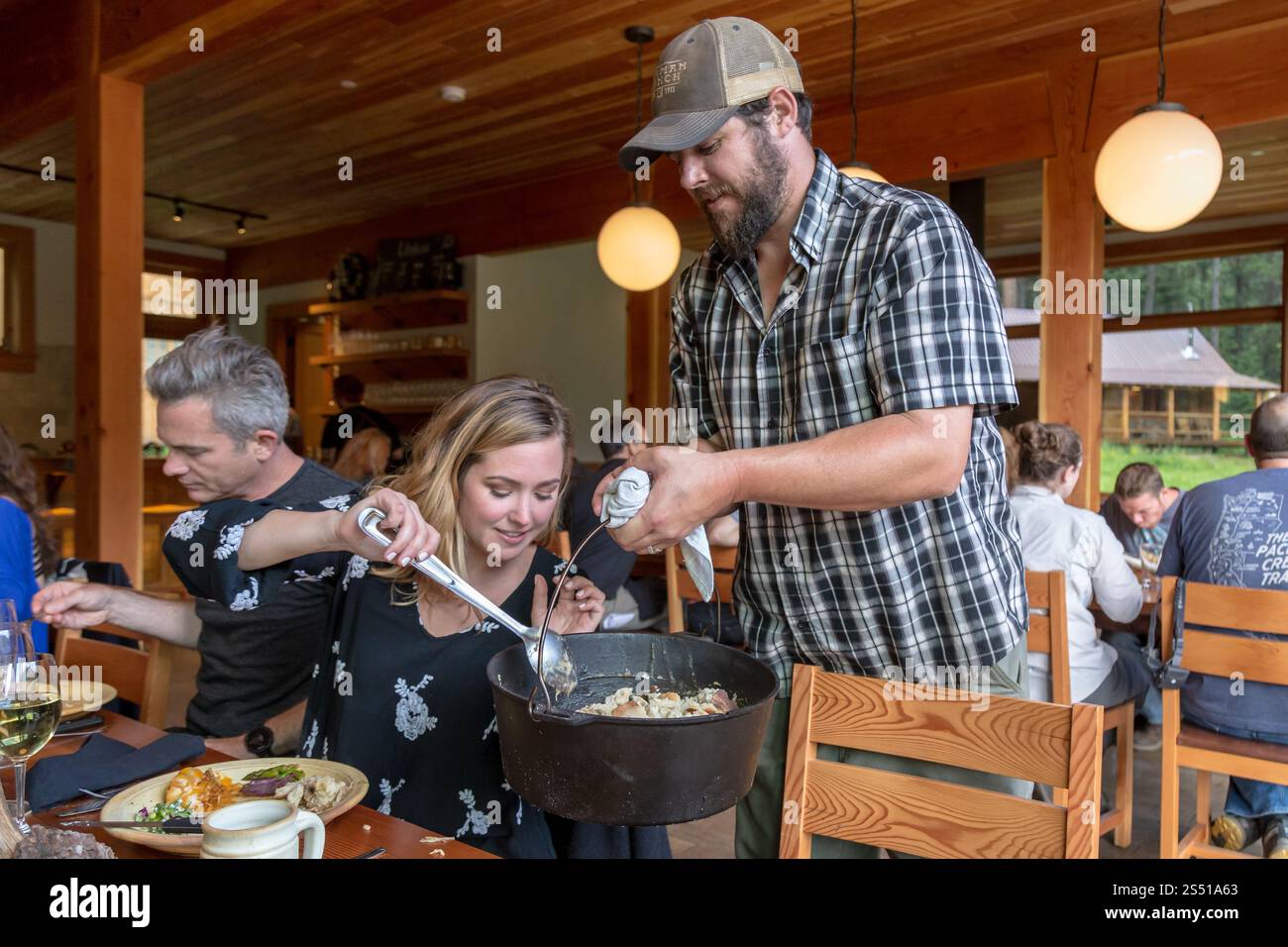 Amici che condividono un pasto comune in un accogliente ristorante rustico, Eagle Cap Wilderness, Oregon Foto Stock