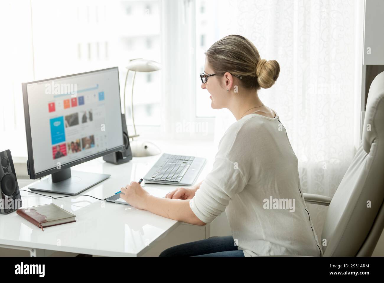 Bella giovane donna che lavora al computer in ufficio con una grande finestra. Bella donna che lavora al computer in ufficio con una grande finestra Foto Stock
