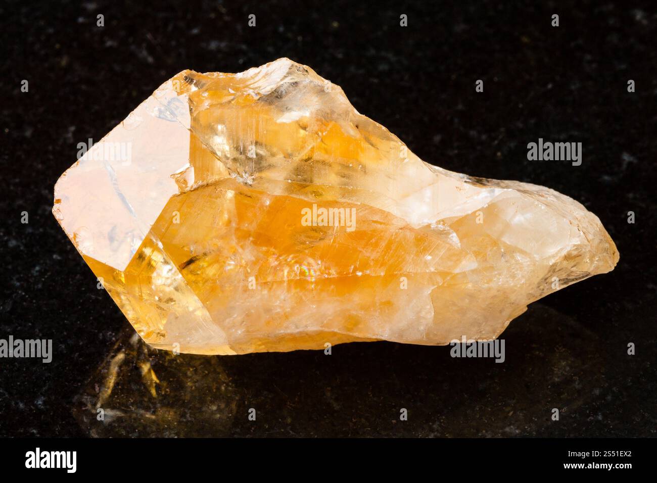 Cristallo di pietra preziosa Citrina su nero. Macro tiro di un campione di roccia naturale - cristallo di Citrine (quarzo giallo) gemma su granito nero Foto Stock