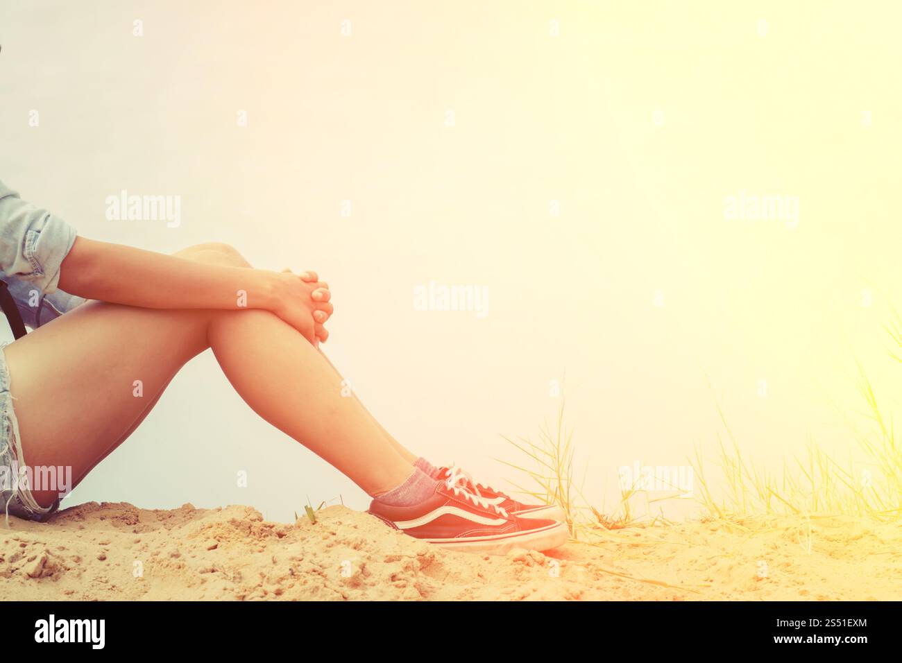 Donna seduta abbracciando le ginocchia con dolore. Foto Stock