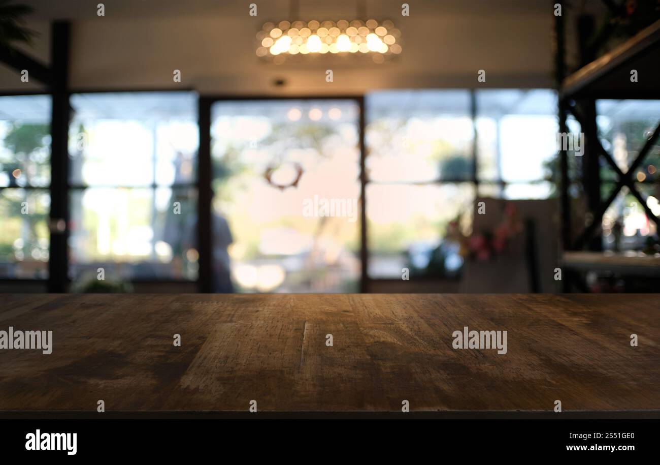 Tavolo vuoto di legno scuro davanti allo sfondo bokeh astratto e sfocato del ristorante. può essere utilizzato per la visualizzazione o il montaggio dei prodotti. Mock-up per Foto Stock