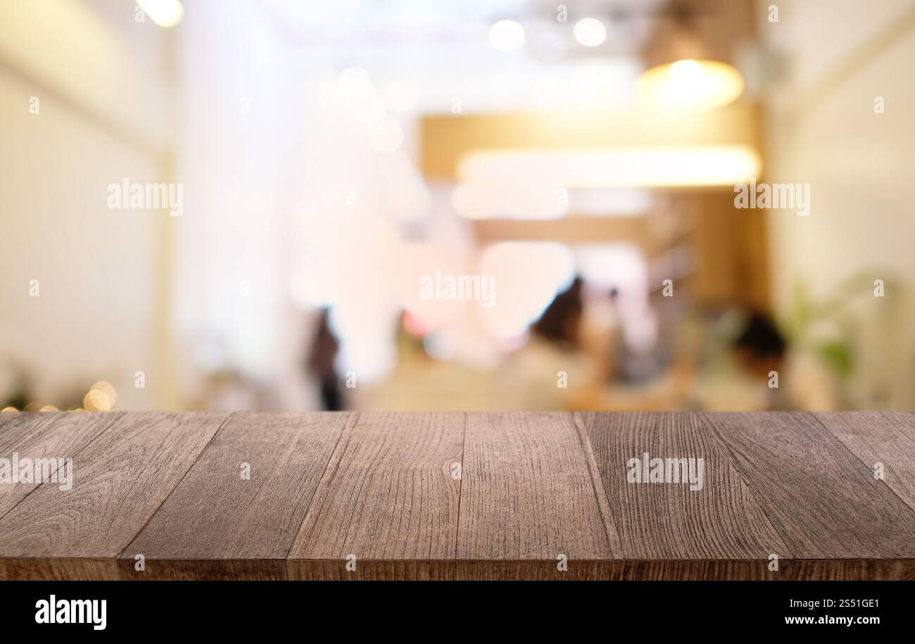 Tavolo vuoto di legno scuro davanti allo sfondo bokeh astratto e sfocato del ristorante. può essere utilizzato per la visualizzazione o il montaggio dei prodotti. Mock-up per Foto Stock