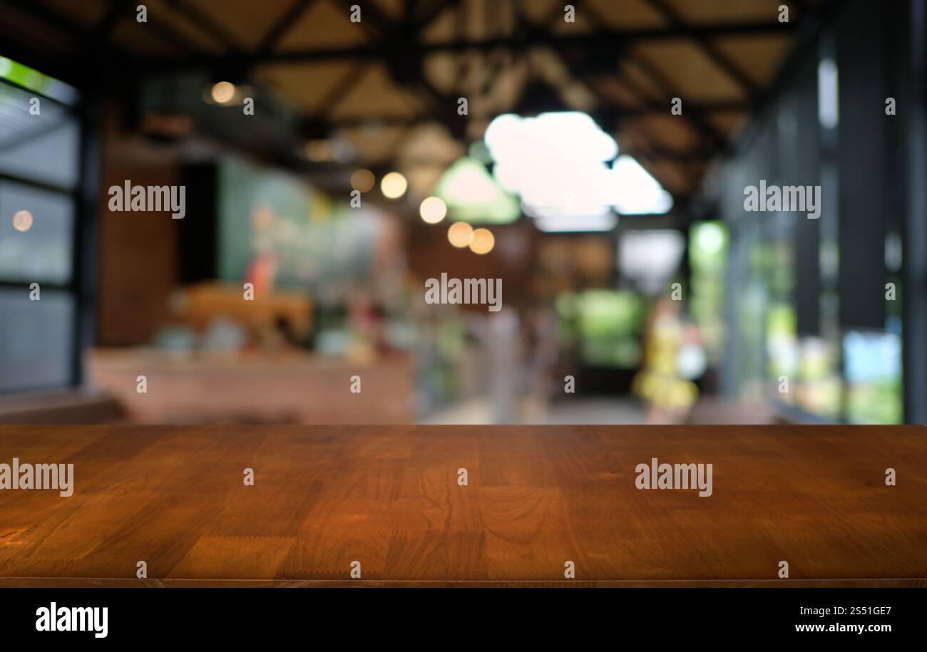 Tavolo vuoto di legno scuro davanti allo sfondo bokeh astratto e sfocato del ristorante. può essere utilizzato per la visualizzazione o il montaggio dei prodotti. Mock-up per Foto Stock