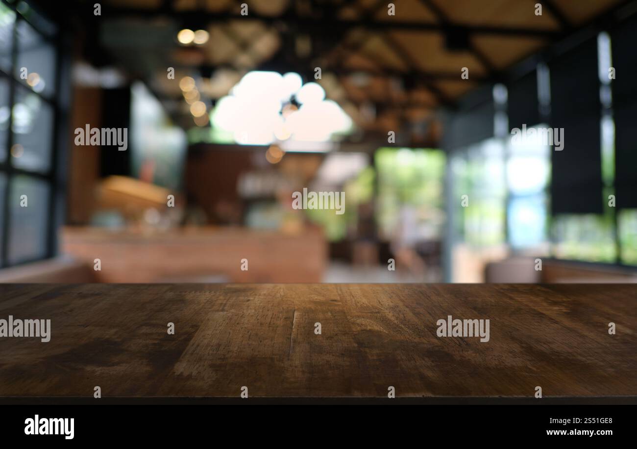 Tavolo vuoto di legno scuro davanti allo sfondo bokeh astratto e sfocato del ristorante. può essere utilizzato per la visualizzazione o il montaggio dei prodotti. Mock-up per Foto Stock