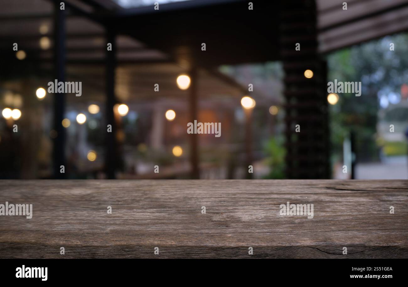 Tavolo vuoto di legno scuro davanti allo sfondo bokeh astratto e sfocato del ristorante. può essere utilizzato per la visualizzazione o il montaggio dei prodotti. Mock-up per Foto Stock