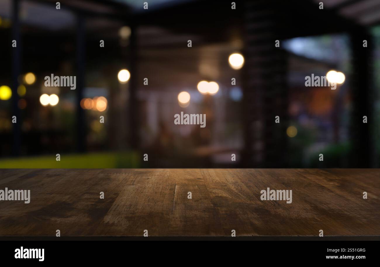 Tavolo vuoto di legno scuro davanti allo sfondo bokeh astratto e sfocato del ristorante. può essere utilizzato per la visualizzazione o il montaggio dei prodotti. Mock-up per Foto Stock