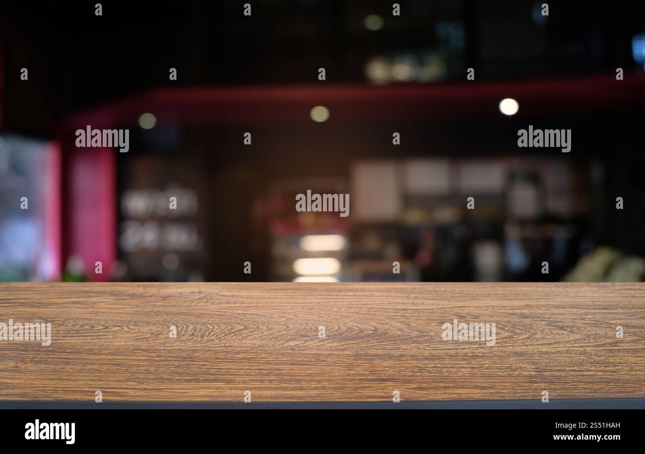 Tavolo vuoto di legno scuro davanti allo sfondo bokeh astratto e sfocato del ristorante. può essere utilizzato per la visualizzazione o il montaggio dei prodotti. Mock-up per Foto Stock