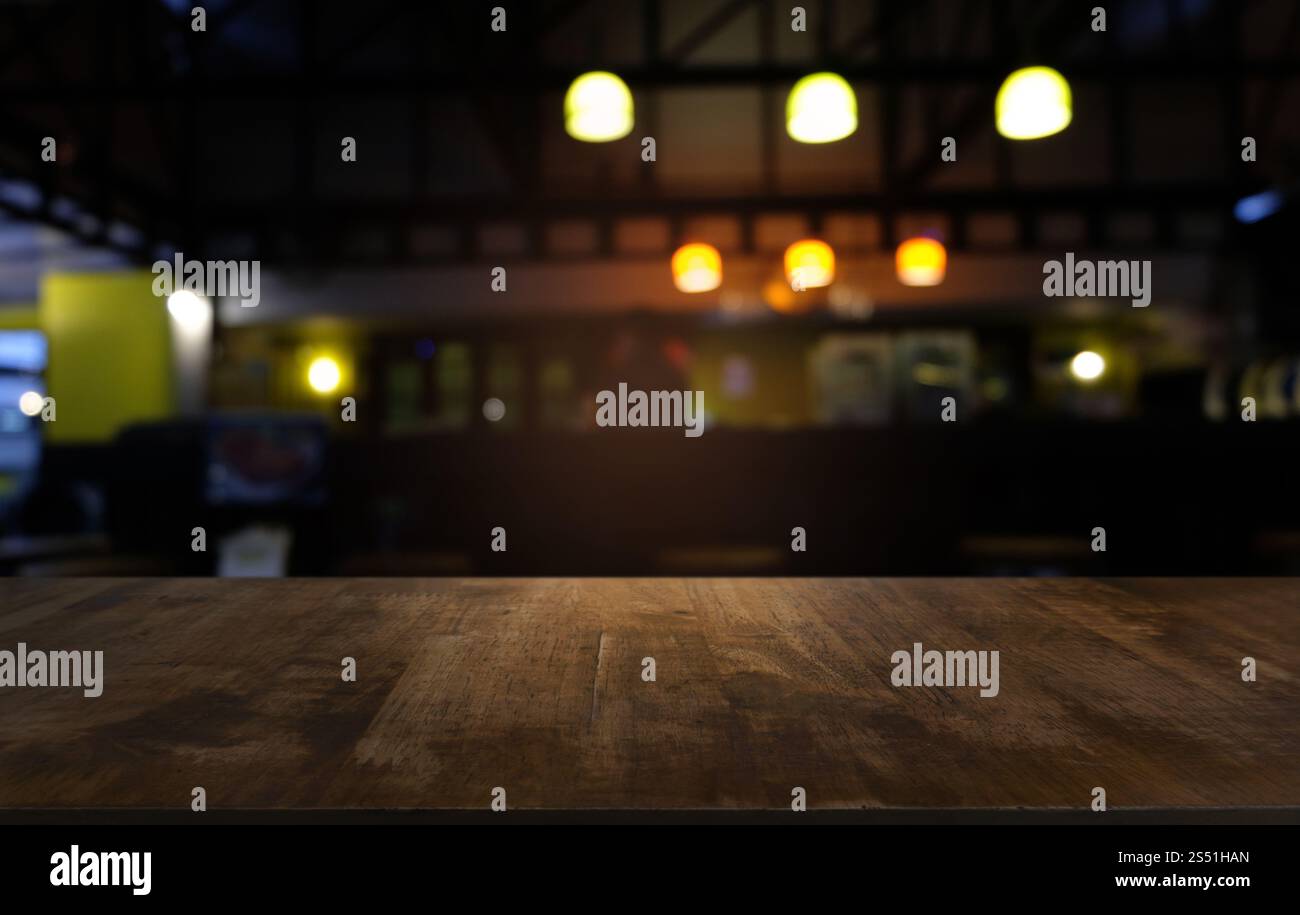 Tavolo vuoto di legno scuro davanti allo sfondo bokeh astratto e sfocato del ristorante. può essere utilizzato per la visualizzazione o il montaggio dei prodotti. Mock-up per Foto Stock