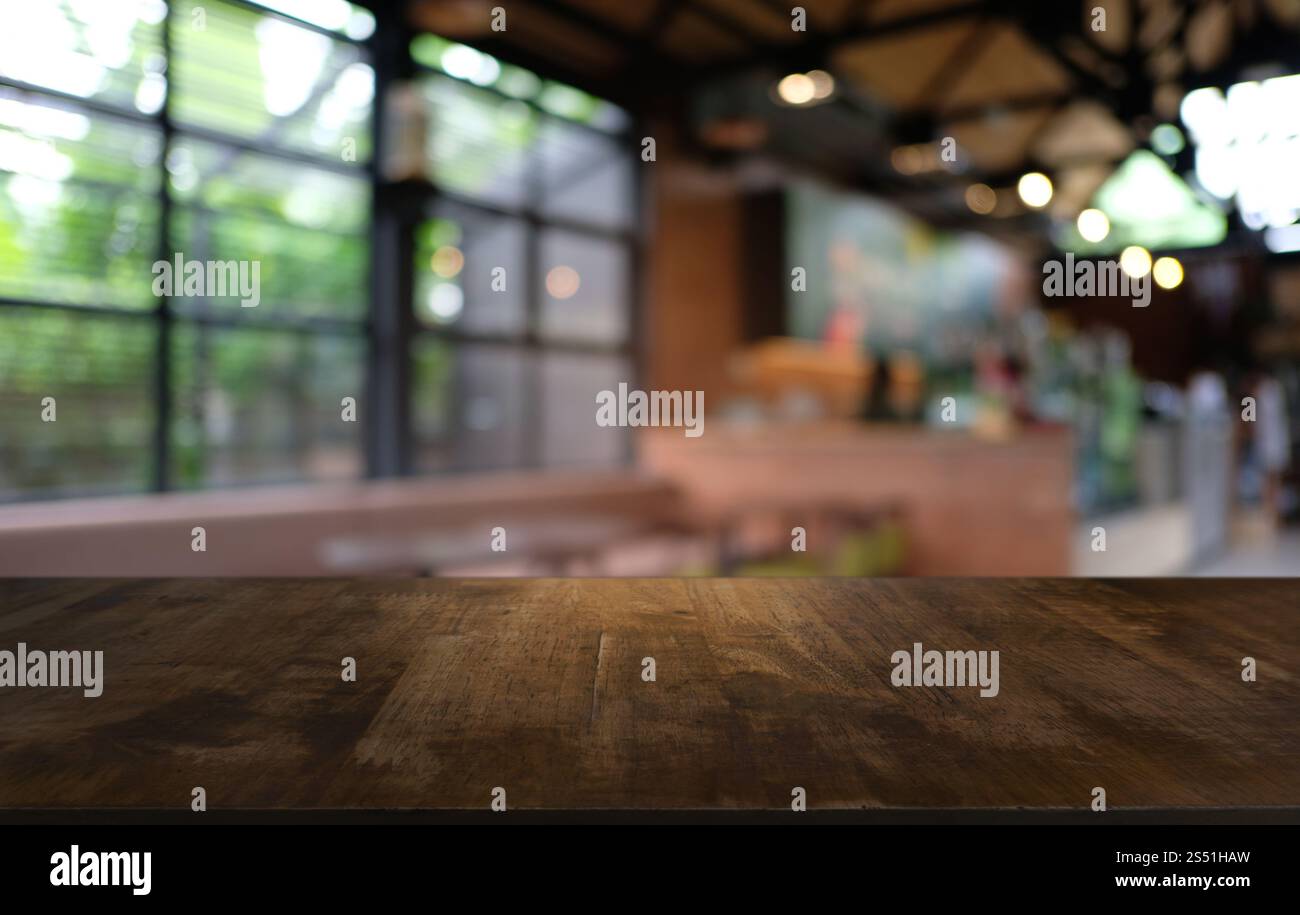Tavolo vuoto di legno scuro davanti allo sfondo bokeh astratto e sfocato del ristorante. può essere utilizzato per la visualizzazione o il montaggio dei prodotti. Mock-up per Foto Stock