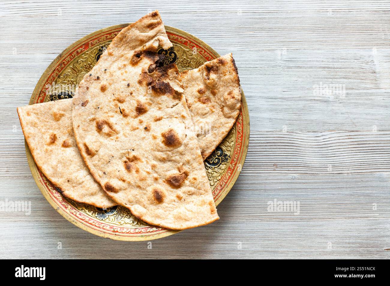 Cucina indiana - Tandoori Roti di tutto il grano pane piatto sulla piastra in ottone sulla tabella grigia Foto Stock