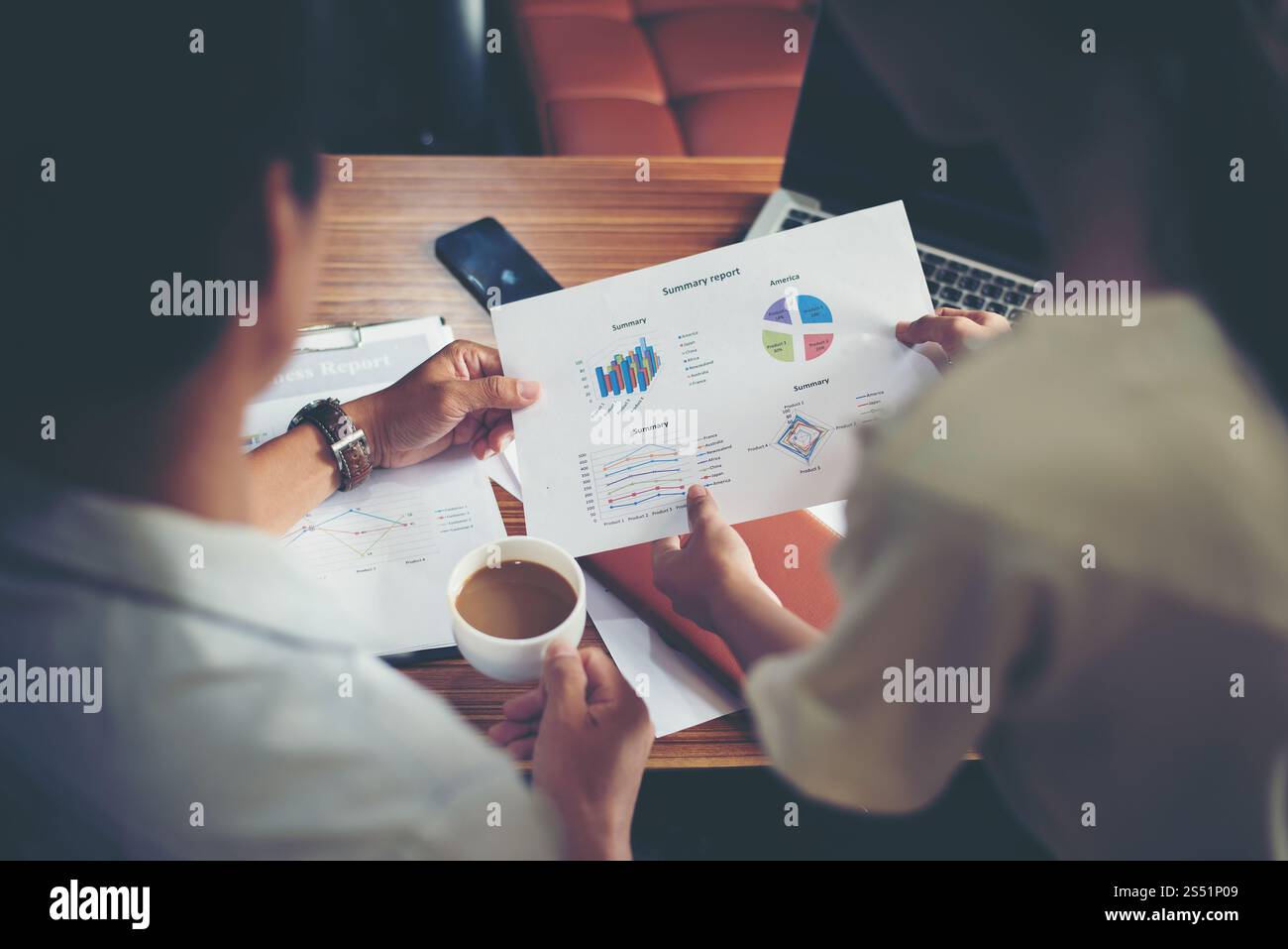 Il capo che tiene una tazza di caffè lavora con la segretaria sull'analisi del grafico finanziario in ufficio. Capo che tiene una tazza di caffè lavora con la segretaria Foto Stock