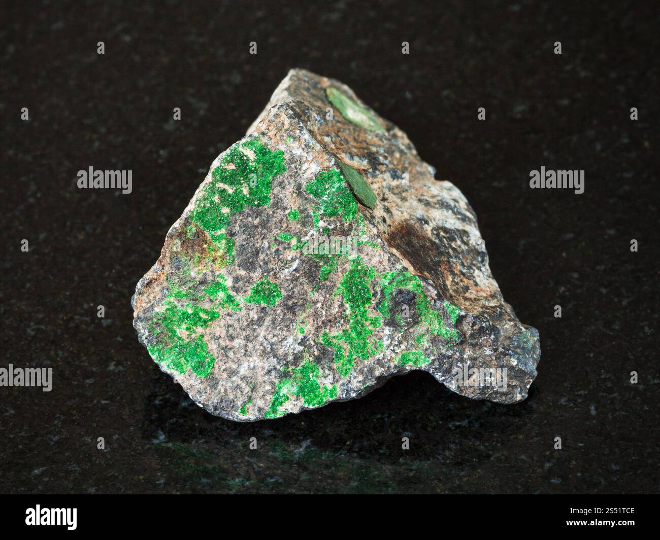 Le riprese in modalità macro di minerale naturale - verde Uvarovite cristalli sulle materie di cromite sulla pietra di granito nero da Monti Urali Foto Stock