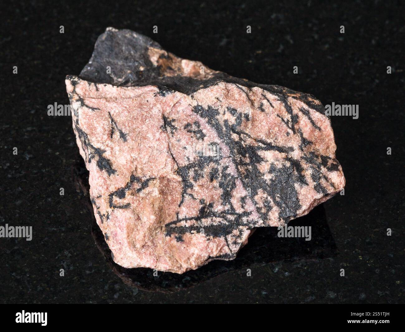 Le riprese in modalità macro di minerali naturali - Rhodonite ruvida sulla pietra di granito nero da Monti Urali Foto Stock