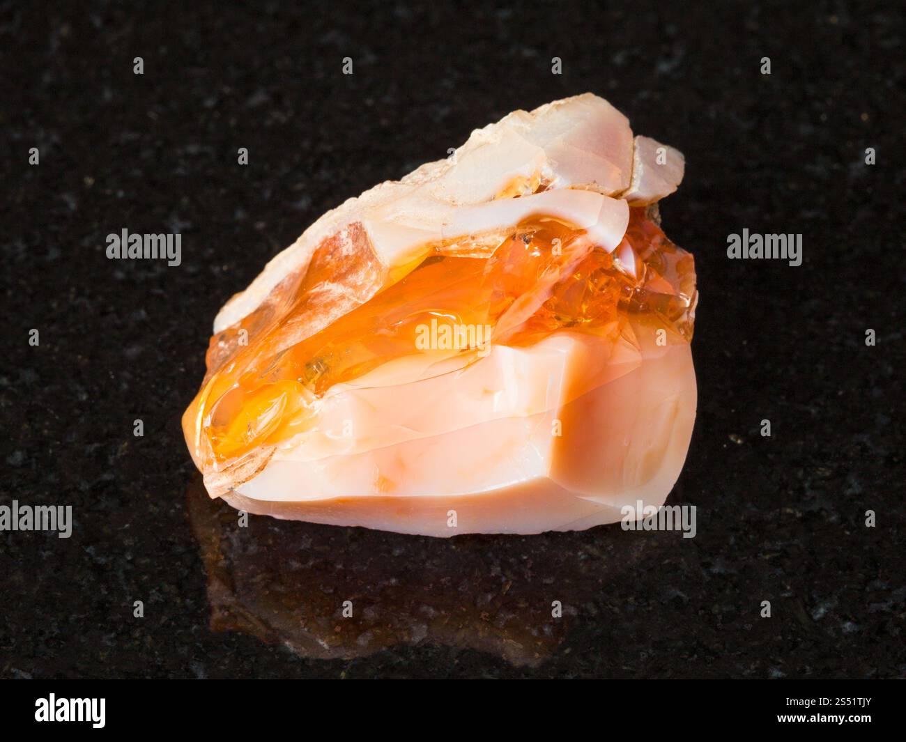 Le riprese in modalità macro di minerali naturali - ruvida opale prezioso e opale di fuoco pietra in granito nero da Monti Urali Foto Stock