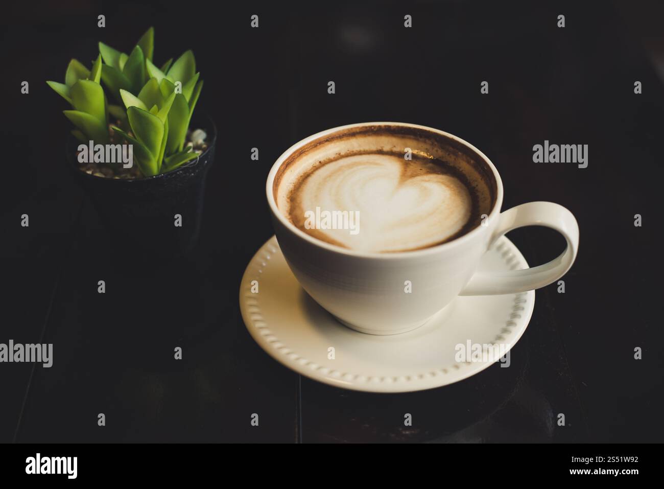 A forma di cuore caffè latte macchiato con cactus sulla tavola di legno. Foto Stock A forma di cuore caffè latte macchiato con cactus sulla tavola di legno. Foto Stock