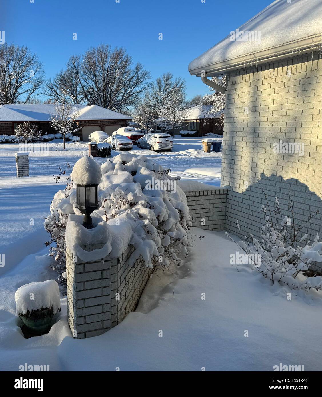 Neve pesante a Wichita, Kansas rivestito di oggetti e alberi. Mostra una strada residenziale e un quartiere e la parte anteriore di una casa con lampioni e pareti in mattoni. - Immagine stock catturata con smartphone