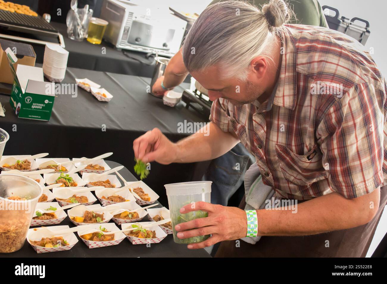 Chef professionista che prepara piatti in un evento culinario in un ambiente moderno Foto Stock