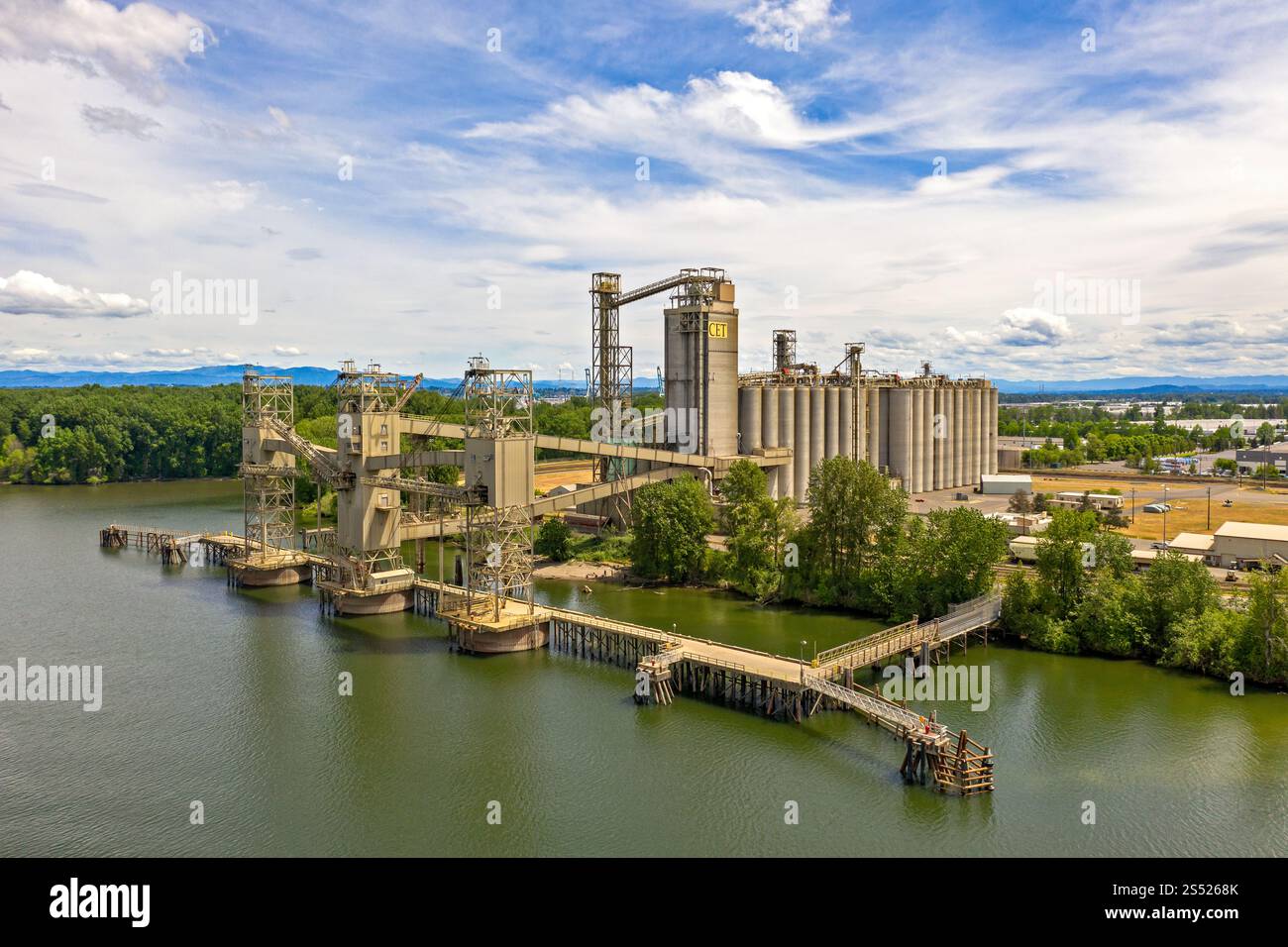 Impianto industriale sul lungomare con colline panoramiche sullo sfondo Foto Stock
