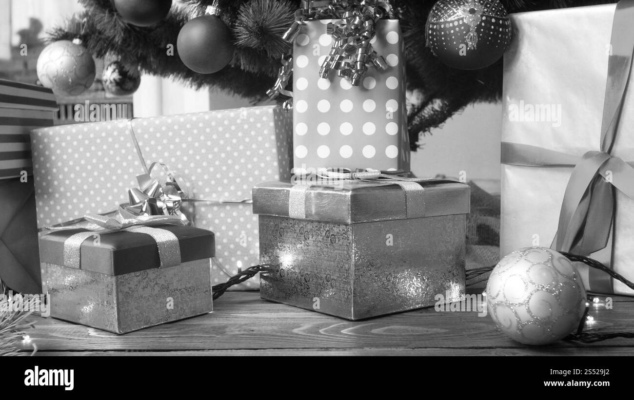Foto in bianco e nero di un'alta pila di regali di Natale sotto l'albero di Natale nel soggiorno. Immagine in bianco e nero di un'alta pila di regali di Natale Foto Stock