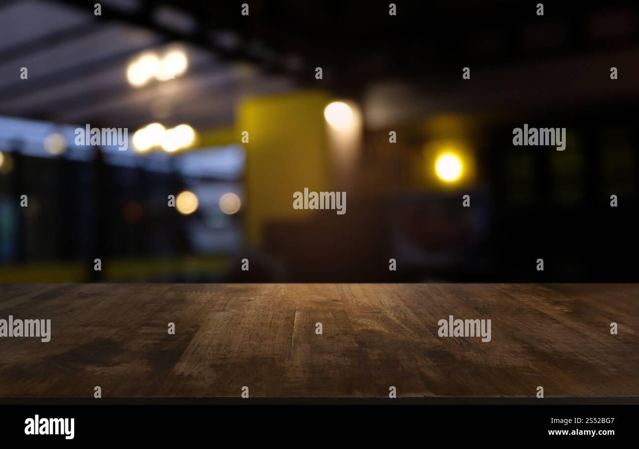 Tavolo vuoto di legno scuro davanti allo sfondo bokeh astratto e sfocato del ristorante. può essere utilizzato per la visualizzazione o il montaggio dei prodotti. Mock-up per Foto Stock